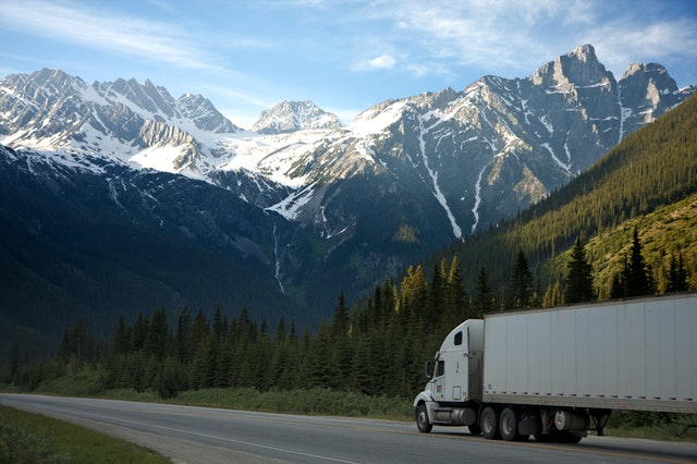 LKW fährt rRichtung Bergen unter einen blauen Himmel